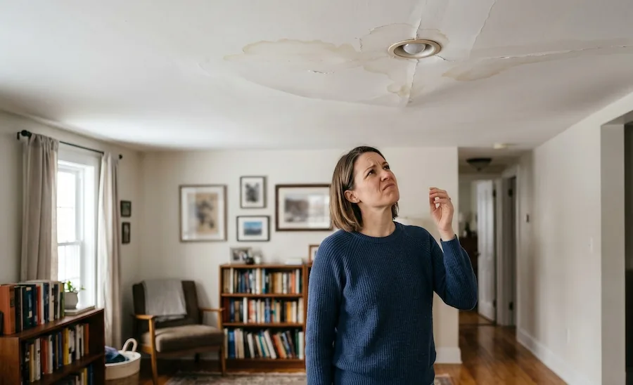 Perth homeowner inspecting ceiling water damage and roof leak stains inside residential property