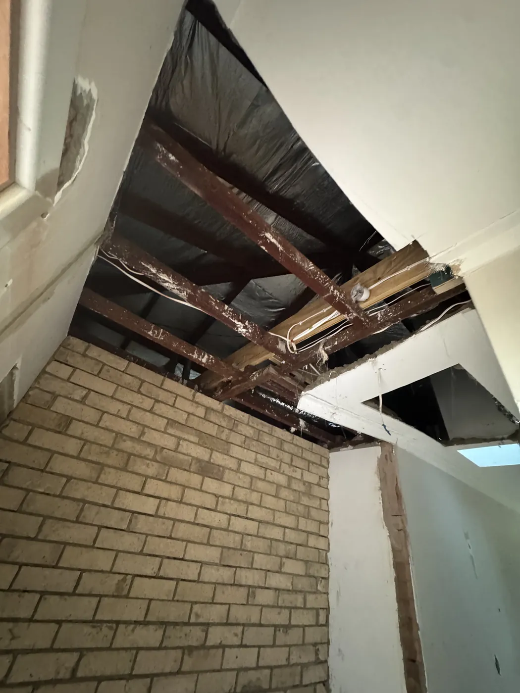Section of ceiling removed above brickwork in a Victoria Park home, with the roof frame on show