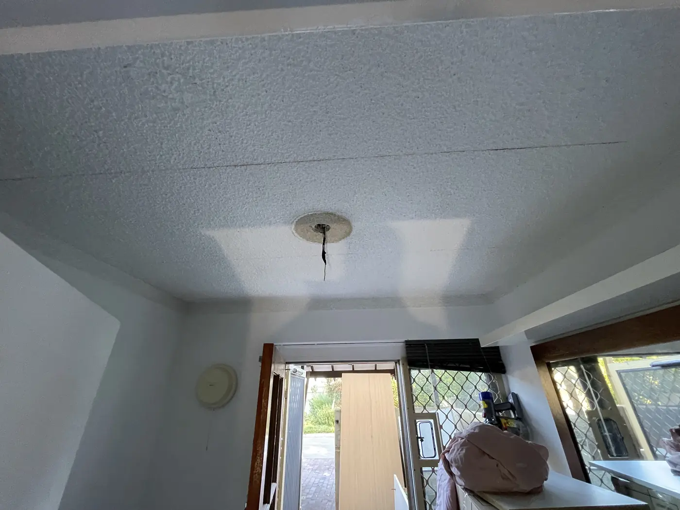 Old textured ceiling and light point before the work in a Bayswater room