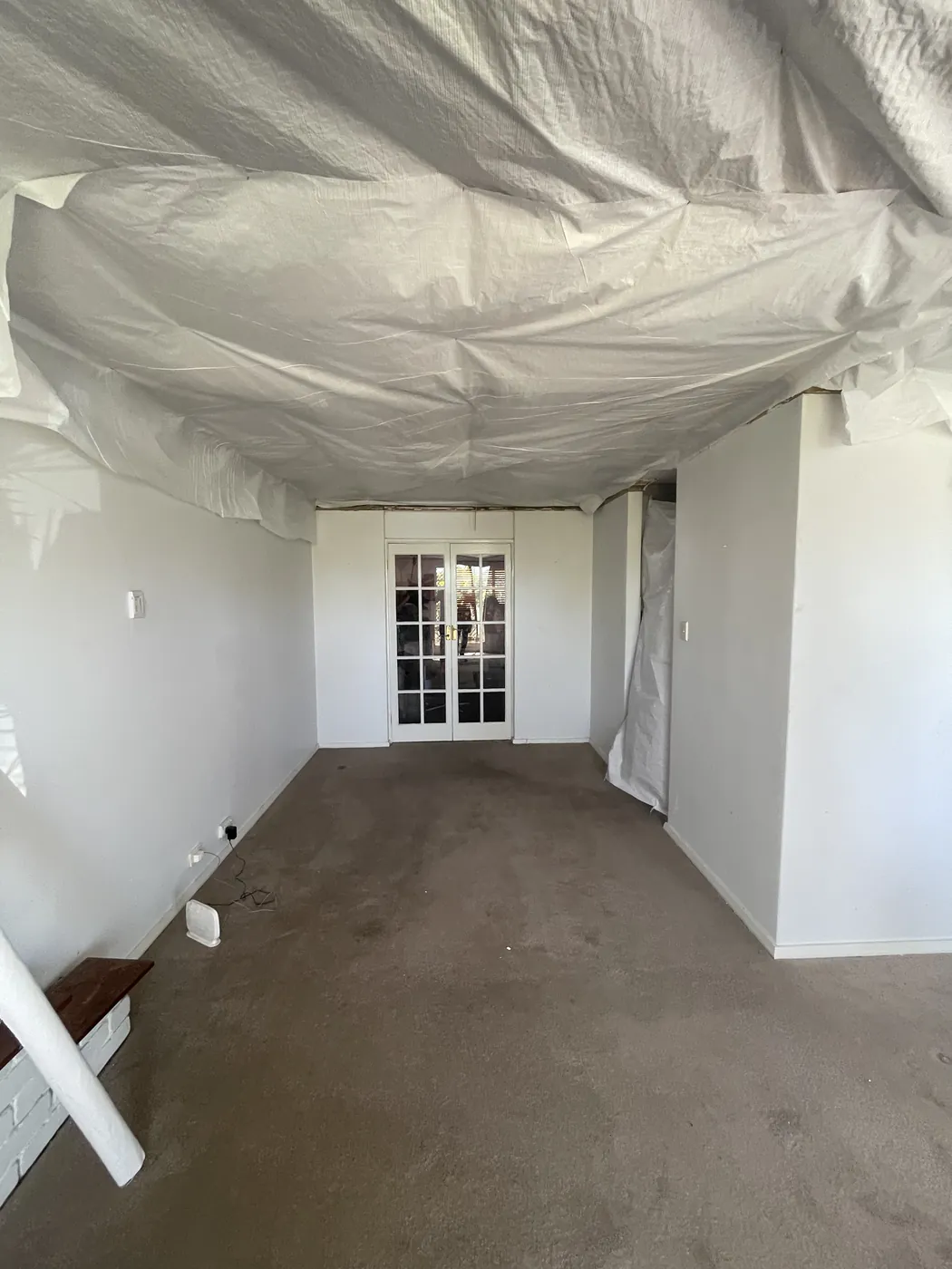 Living room in Joondalup with plastic sheeting fixed across the ceiling frame