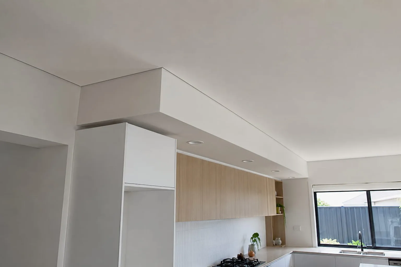 A kitchen bulkhead dropped down and set with downlights through it
