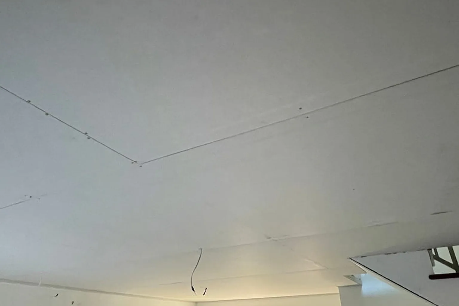 A new plasterboard ceiling screwed up and waiting to be flushed, sheet joins still showing